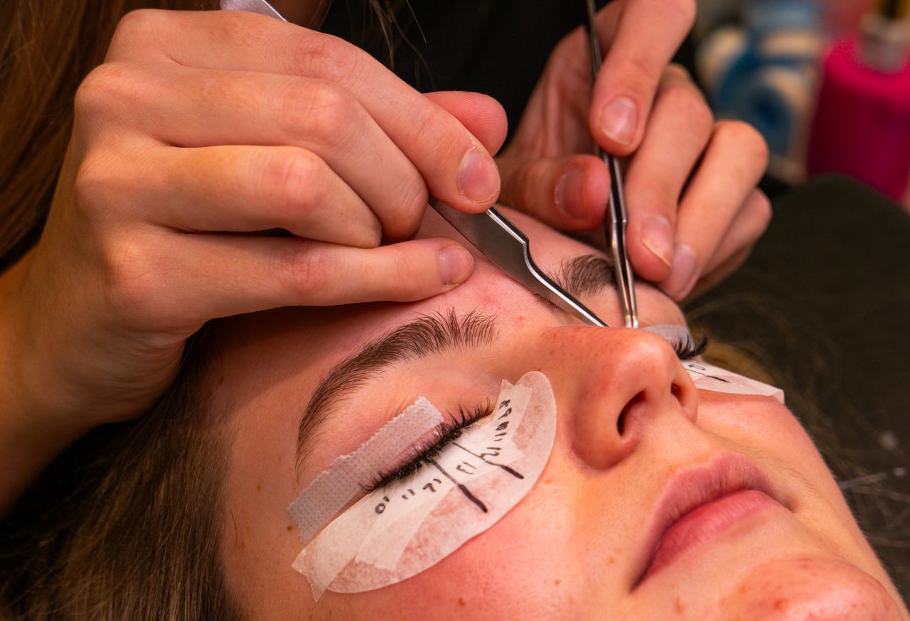 Usługi A detailed view of a lash extension beauty procedure with close-up on tools and eye.